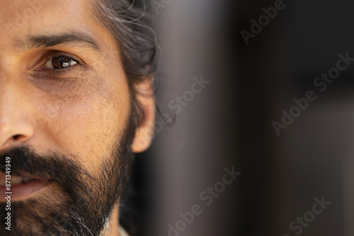 Close-up of Indian male with beard, focusing on eye and facial hair, copy space photo