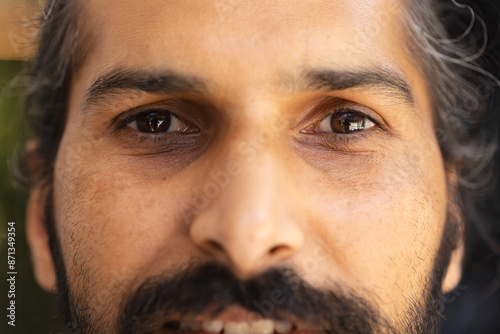 Close-up of Indian male face with beard and mustache, looking directly ahead photo