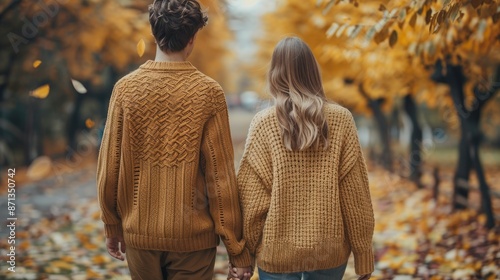 Couple Walking in Cozy Sweaters through Autumn Park with Golden Leaves photo