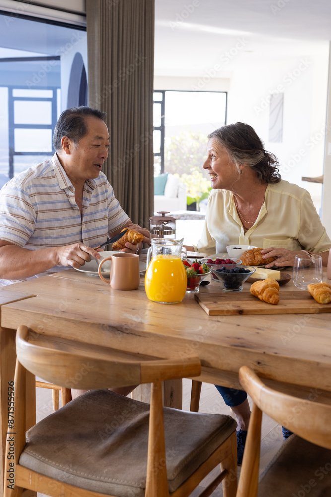 Enjoying breakfast together, senior couple smiling and talking at dining table Enjoying breakfast together, senior couple smiling and talking at dining table