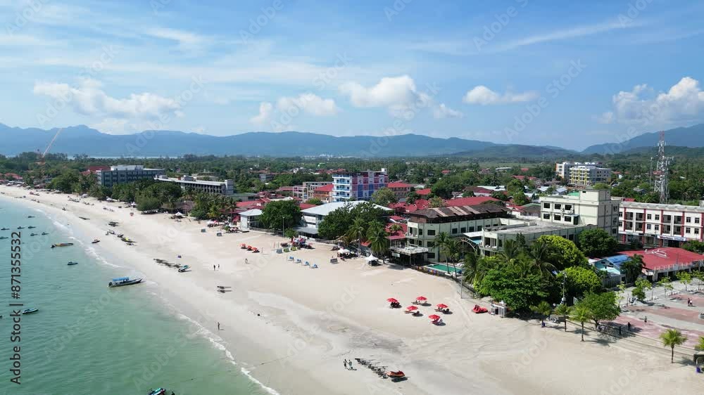 Drone view of Cenang beach with tourists and mountains at background on a sunny day in Malaysia. Drone view of Cenang beach with tourists and mountains at background on a sunny day in Malaysia.