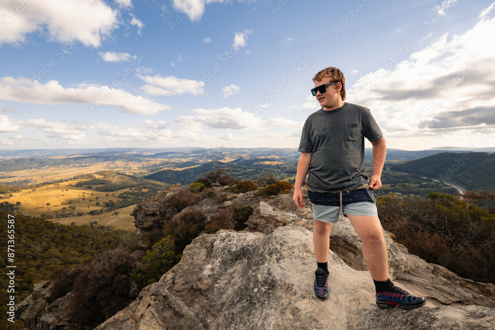Fototapeta premium Boy standing on rock at Hassans Walls Lookout watching valley below