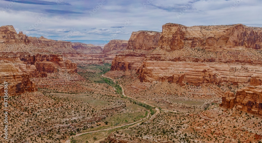 Fototapeta premium Dirt road going through a Canyon and tall Buttes. Buckhorn Wash, Utah, United States of America.