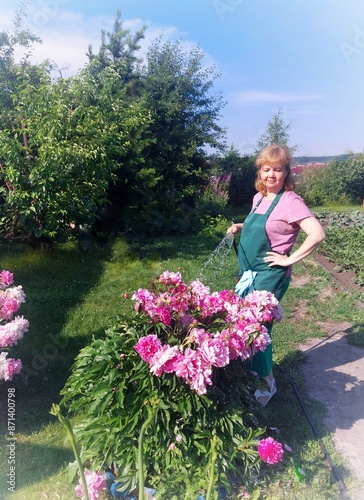 girl with flowersa female gardener waters flowers in her garden. photo