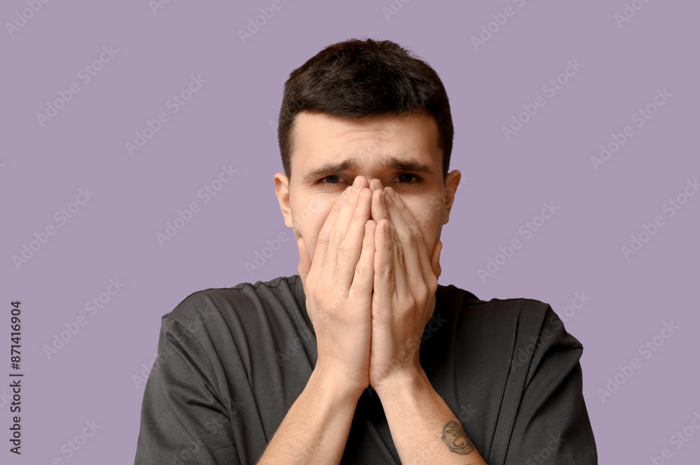 Handsome young man feeling bad smell on purple background Handsome young man feeling bad smell on purple background