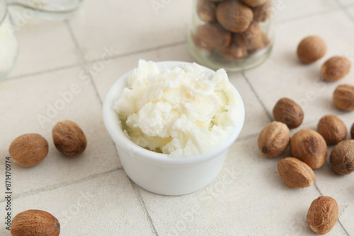 Bowl with shea butter and nuts on light tile table