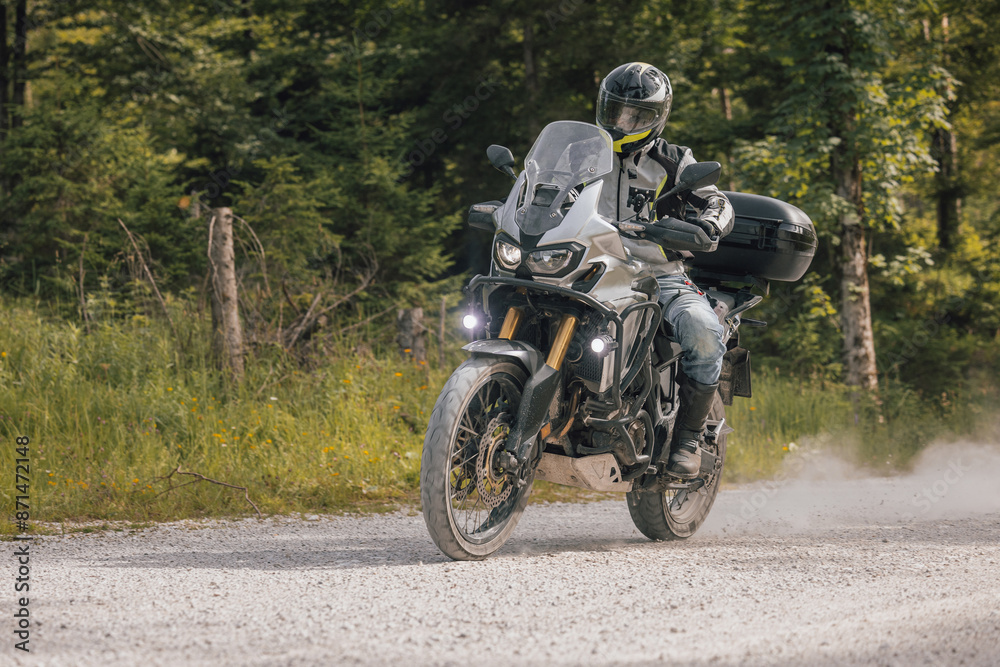 Modern adventure motorcycle on a ride on gravel surface. Motorcycling in nature or offroad, enjoying freedom. Motorbike in the woods. Making a turn