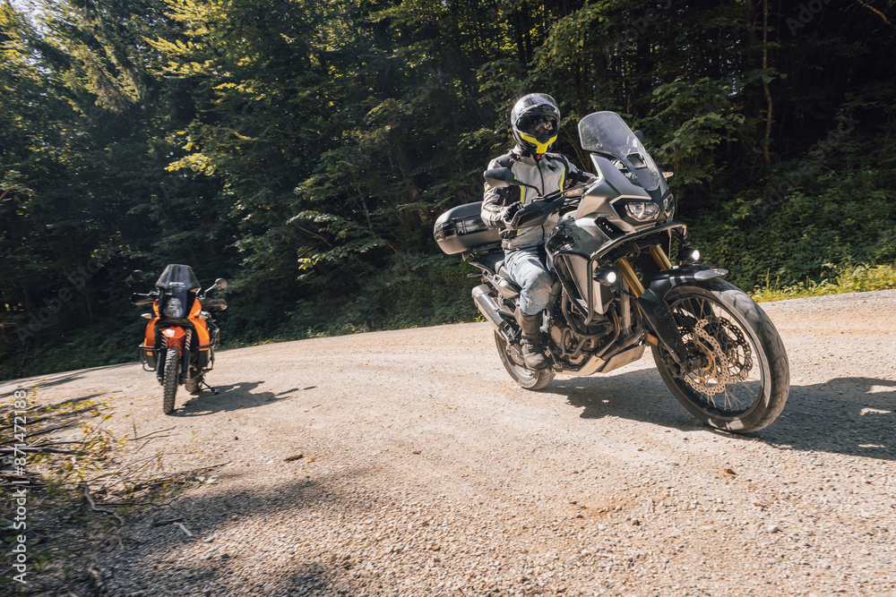 Modern adventure motorcycle on a ride on gravel surface. Motorcycling in nature or offroad, enjoying freedom. Motorbike in the woods. Bike on a bend