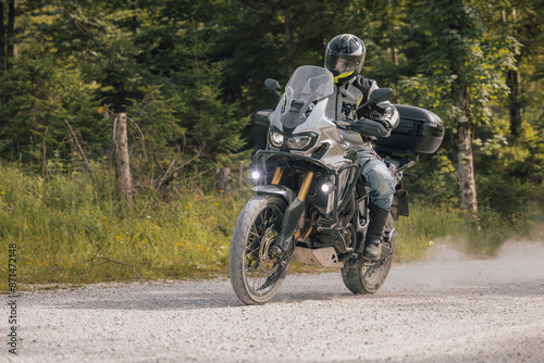 Obraz na płótnie Modern adventure motorcycle on a ride on gravel surface. Motorcycling in nature or offroad, enjoying freedom. Motorbike in the woods. Making a turn w salonie