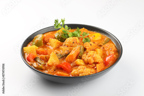 Mixed veg curry or kurma tasty indian dish made of vegetables like cauliflower, carrot, potato, green peas and garnished with onion pieces and leaf placed  photo