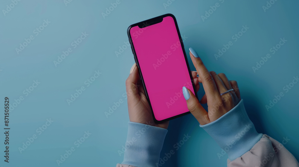 Person using smartphone with pink screen on soft blue background, composition with pastel colors, top view Person using smartphone with pink screen on soft blue background, composition with pastel colors, top view