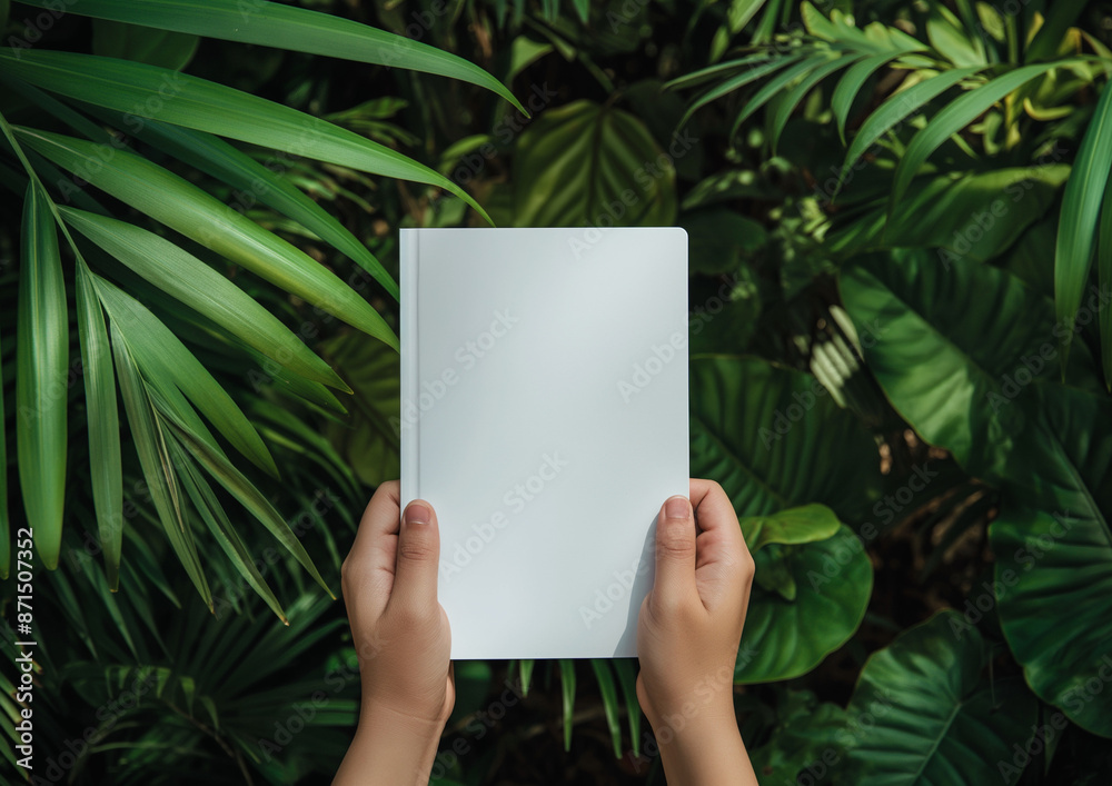 A mockup of an A5 white hardcover book in hands, against a nature background of green leaves and sunlight A mockup of an A5 white hardcover book in hands, against a nature background of green leaves and sunlight