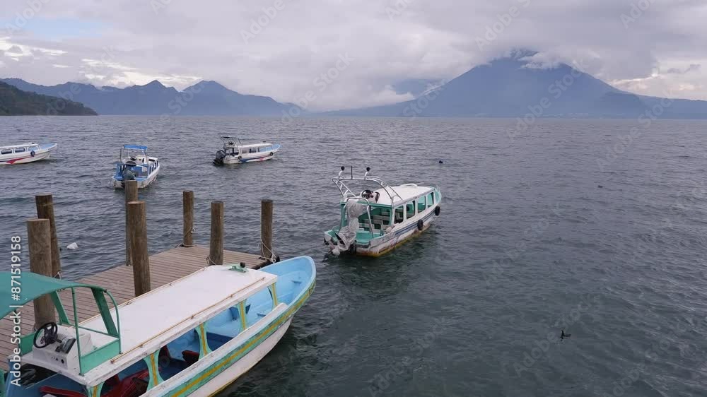 Heavy cloud hangs over Lake Atitlan and volcano, boats moored at dock Heavy cloud hangs over Lake Atitlan and volcano, boats moored at dock