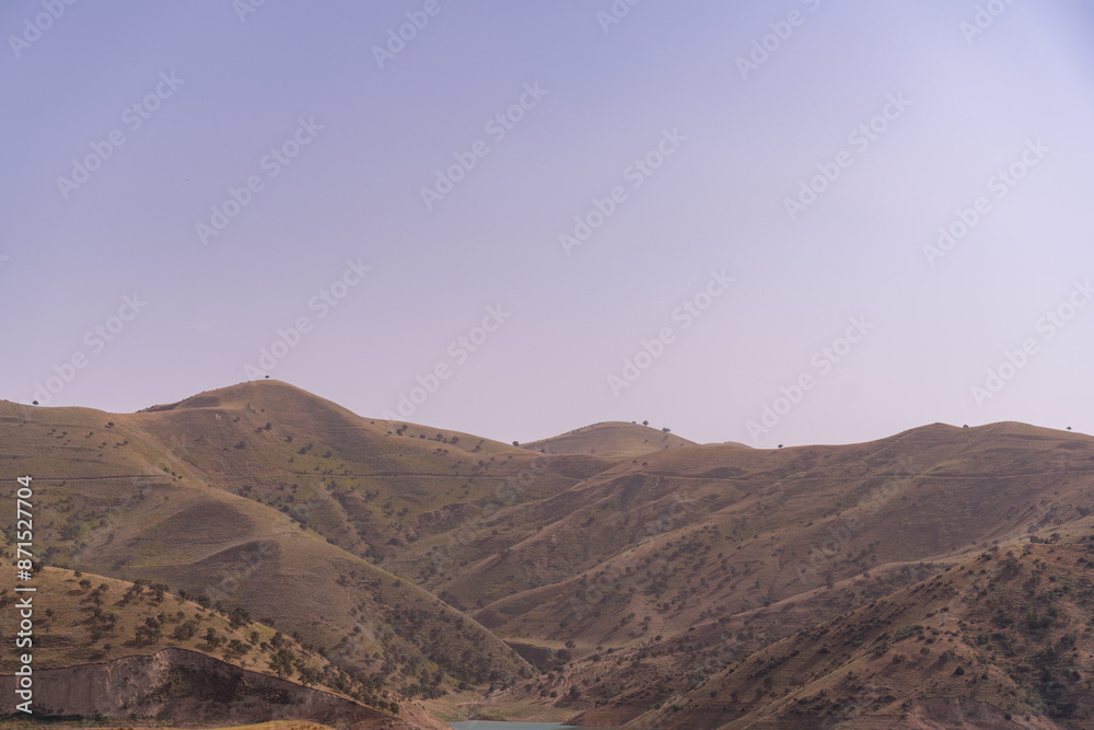 Fototapeta premium The sky is clear and the mountains are covered in green grass