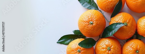  A collection of oranges topped with green leaves on a pristine white table against a crisp white backdrop