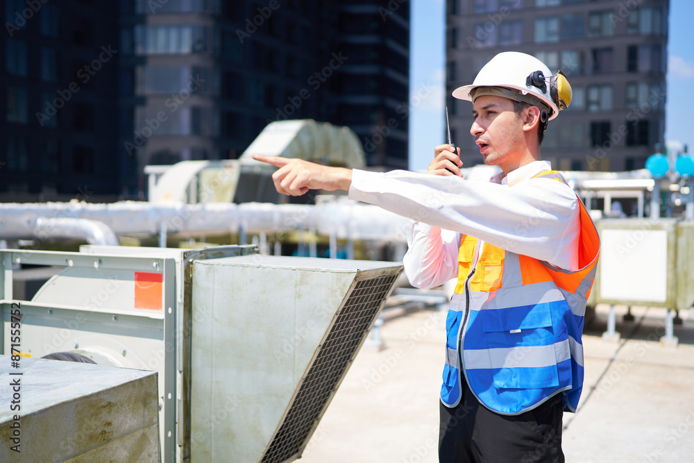 Technician talking on walkie talkie and checking pipeline valves or water tank area at urban industrial site Technician talking on walkie talkie and checking pipeline valves or water tank area at urban industrial site