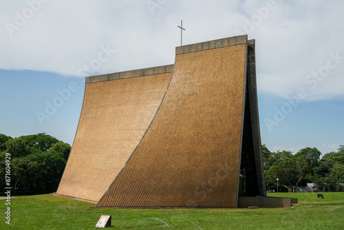 The Luce Memorial Chapel at Tunghai University stands majestically against the backdrop of a clear blue sky, its striking modern architecture beautifully complemented by the lush greenery surrounding  photo