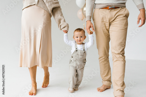One year old son holding hands with mom and dad