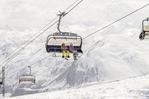 People on a chairlift ascend a ski slope. In the background snowy mountain ridge. Active winter holidays in the mountains. Georgia photo