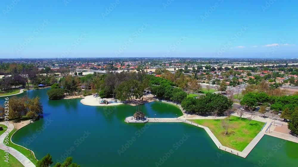 Aerial Forward Descending Beautiful Shot Of Pond In Centennial Park By Residential City On Sunny Day - Los Angeles, California Aerial Forward Descending Beautiful Shot Of Pond In Centennial Park By Residential City On Sunny Day - Los Angeles, California