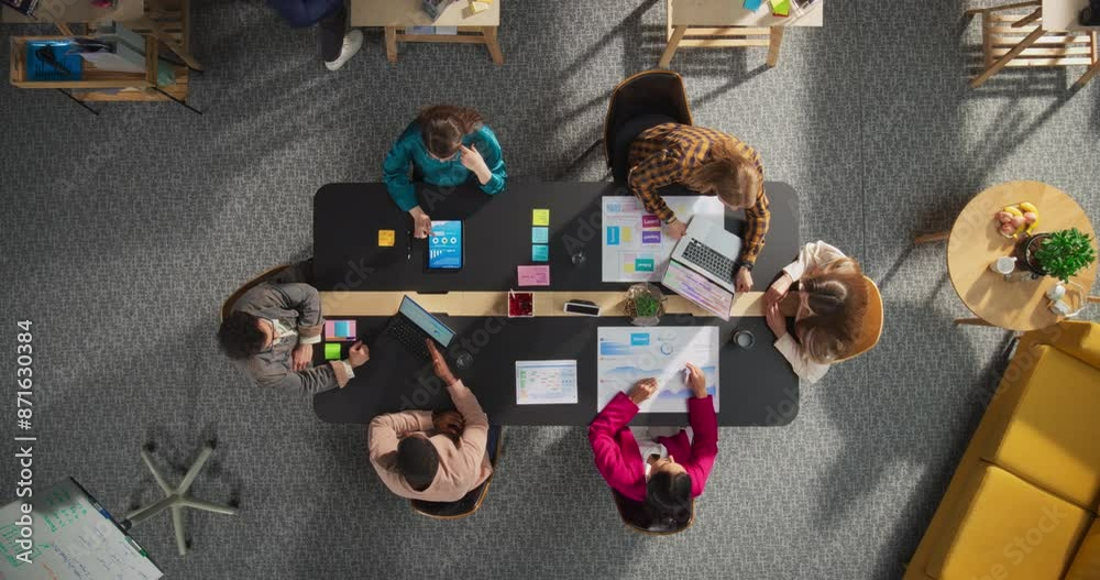Top Down View of Young, Diverse Entrepreneurs in a Colorful Office, Solving Problems and Designing Software, Using laptop, Tablets, and Creative New Project at Conference Table. Productive Teamwork