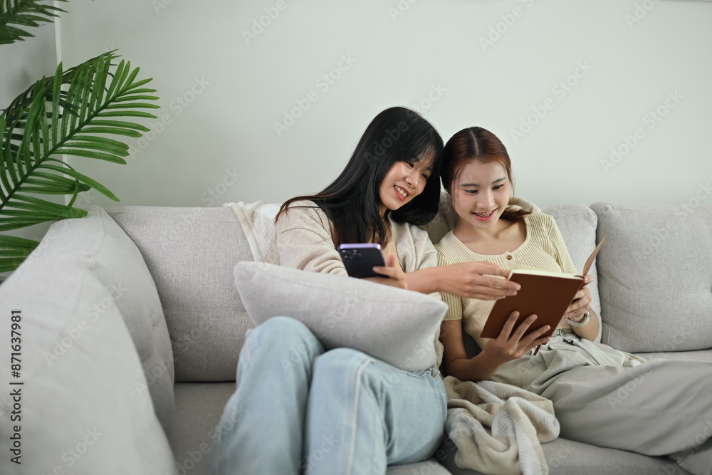 Two happy young female friends relaxing on couch enjoy spending leisure time together Two happy young female friends relaxing on couch enjoy spending leisure time together