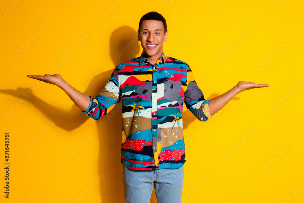 Photo portrait of nice young male compare hold empty space dressed stylish colorful garment isolated on yellow color background Photo portrait of nice young male compare hold empty space dressed stylish colorful garment isolated on yellow color background