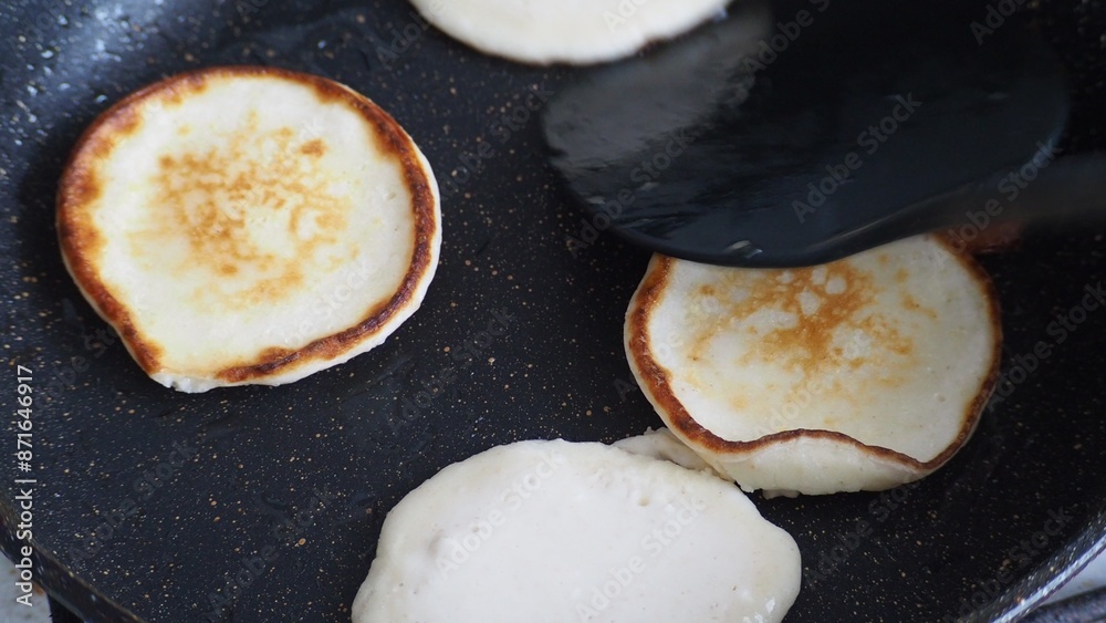 Housewife woman bakes pancakes for breakfast and pours dough into hot frying pan. Homemade pancakeson glass-ceramic stove in kitchen. Ingredients for making pancakes. Selective focus. Housewife woman bakes pancakes for breakfast and pours dough into hot frying pan. Homemade pancakeson glass-ceramic stove in kitchen. Ingredients for making pancakes. Selective focus.