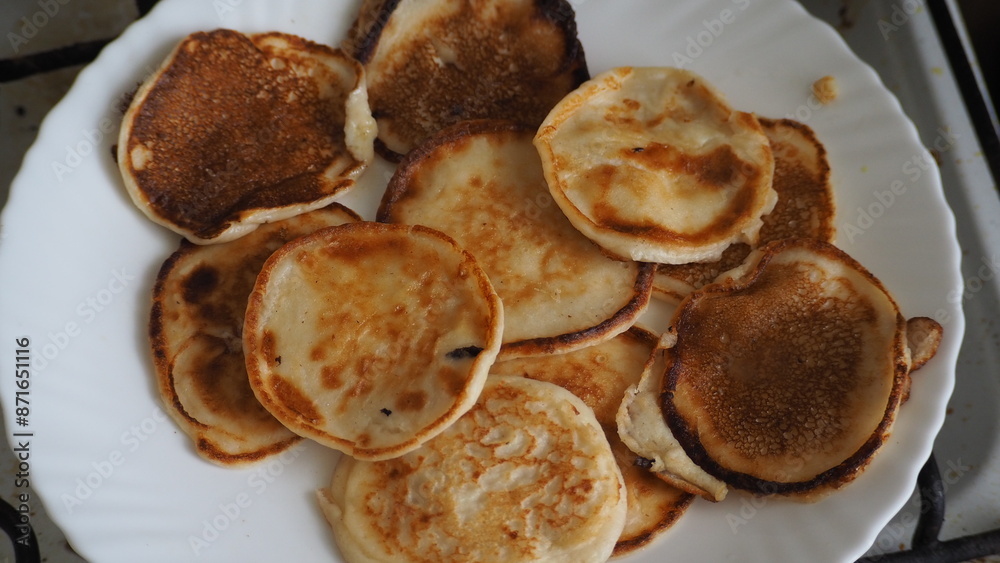 Housewife woman bakes pancakes for breakfast and pours dough into hot frying pan. Homemade pancakeson glass-ceramic stove in kitchen. Ingredients for making pancakes. Selective focus. Housewife woman bakes pancakes for breakfast and pours dough into hot frying pan. Homemade pancakeson glass-ceramic stove in kitchen. Ingredients for making pancakes. Selective focus.