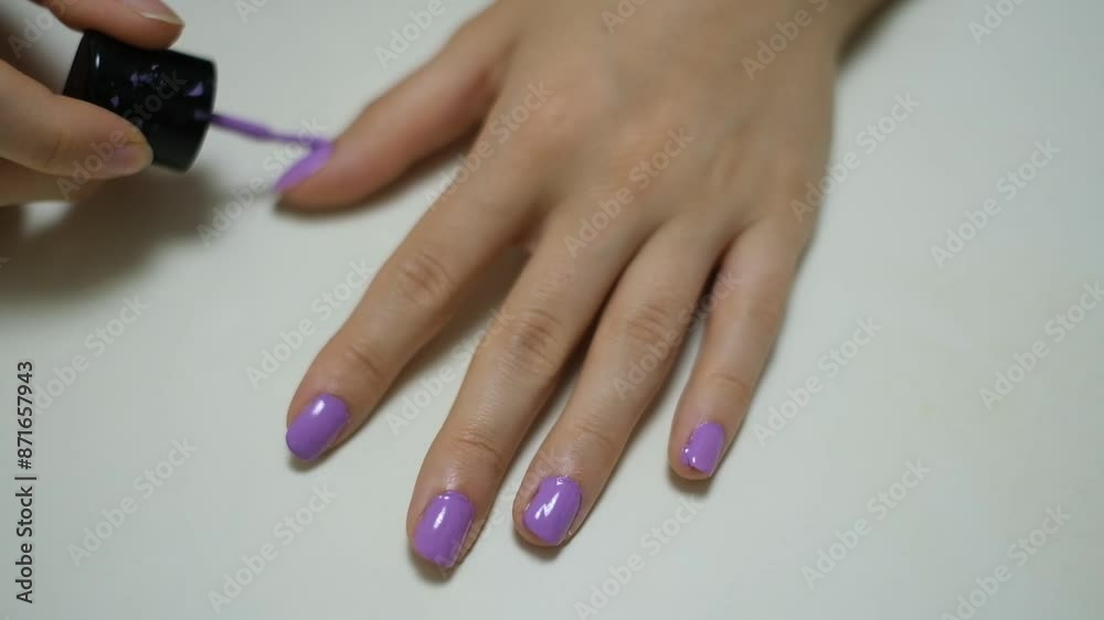 Close-up nail polish application. A woman applying purple nail polish. Nail care. Personal care and beauty. Close-up nail polish application. A woman applying purple nail polish. Nail care. Personal care and beauty.