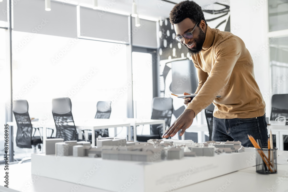 Young man in casual clothes working on miniature and looking involved Young man in casual clothes working on miniature and looking involved