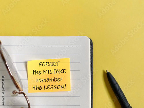 Inspirational quote - Forget the mistake remember the lesson on adhesive notepaper with copy space background. Stock photo.