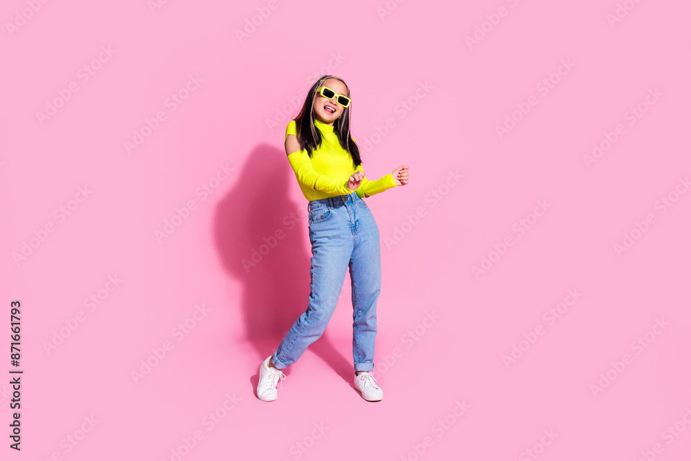 Full size photo of pretty girl with dyed hairstyle dressed yellow shirt jeans in sunglass dancing isolated on pink color background Full size photo of pretty girl with dyed hairstyle dressed yellow shirt jeans in sunglass dancing isolated on pink color background