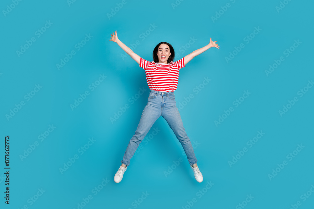 Full length photo of shiny attractive lady dressed red t-shirt jumping high like star empty space isolated blue color background Full length photo of shiny attractive lady dressed red t-shirt jumping high like star empty space isolated blue color background