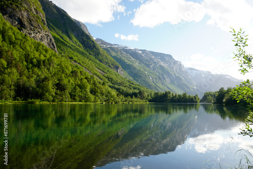 Landscapes of Norway. Beautiful view of the river at the border of the fjord. Mountains and forests. Reflection in water.