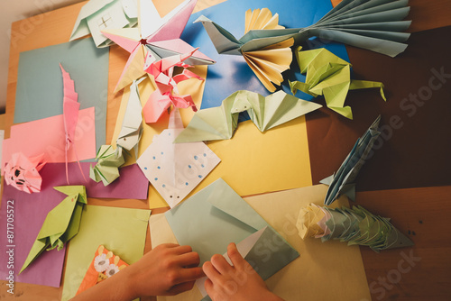 preschool child making origami animals with colorfull papers
