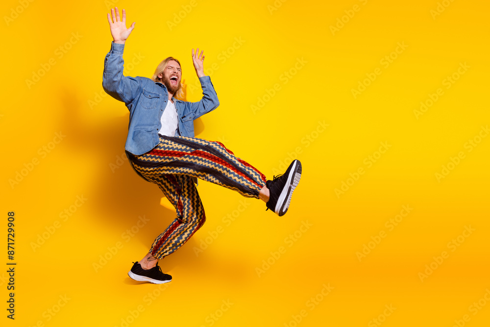 Full size photo of pretty young guy dancing singing wear trendy jeans outfit isolated on yellow color background Full size photo of pretty young guy dancing singing wear trendy jeans outfit isolated on yellow color background