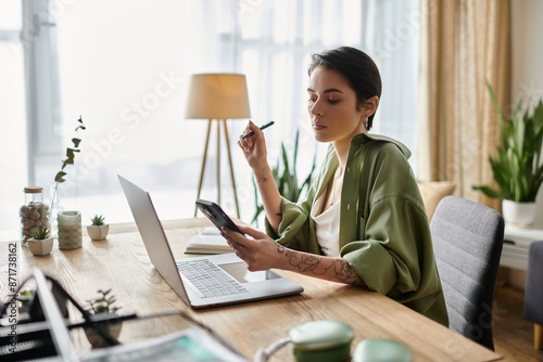 Φωτογραφία A woman is working from home on her laptop and phone.
