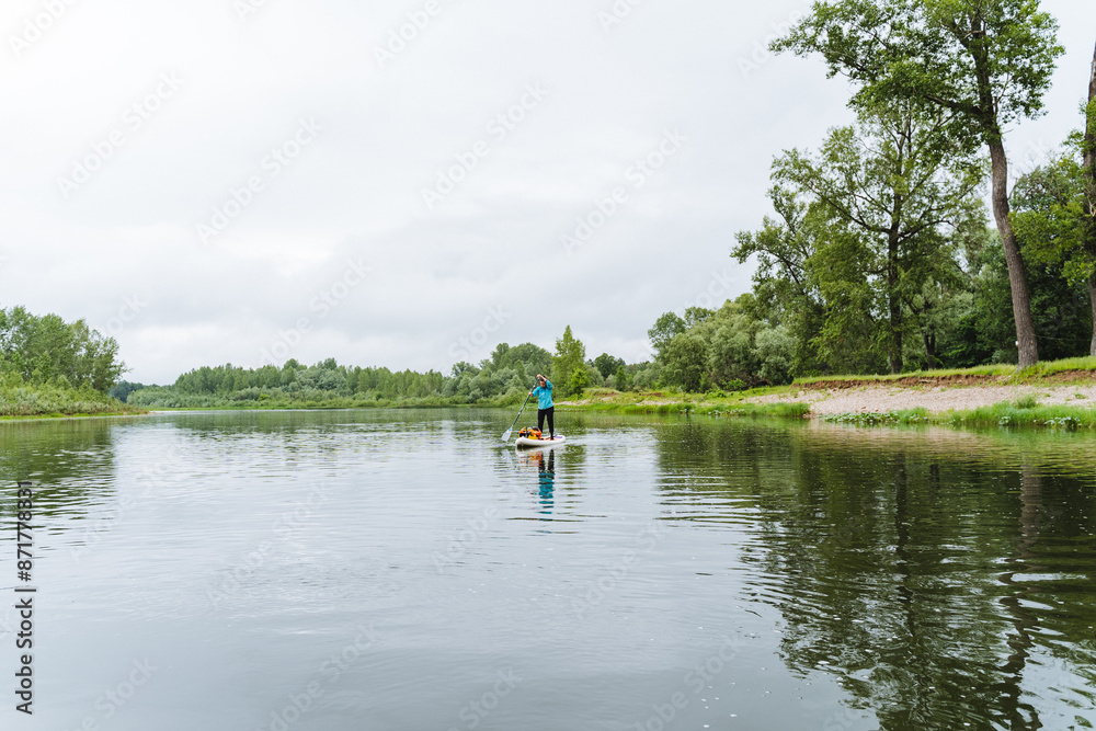 Rafting on the river among the trees on a SUP, SUP boarding, rowing standing, traveling on the lake on a board with a paddle. Rafting on the river among the trees on a SUP, SUP boarding, rowing standing, traveling on the lake on a board with a paddle.