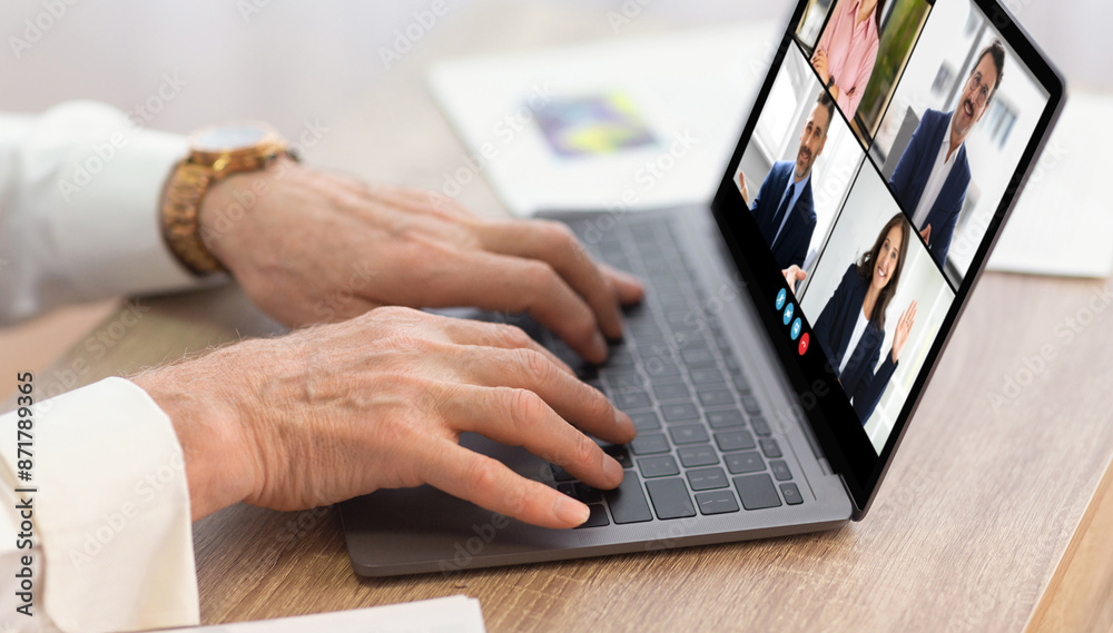 A person is typing on a laptop during a video conference meeting with four other people. The laptop screen shows four video boxes with different people, each in their own workspace. A person is typing on a laptop during a video conference meeting with four other people. The laptop screen shows four video boxes with different people, each in their own workspace.