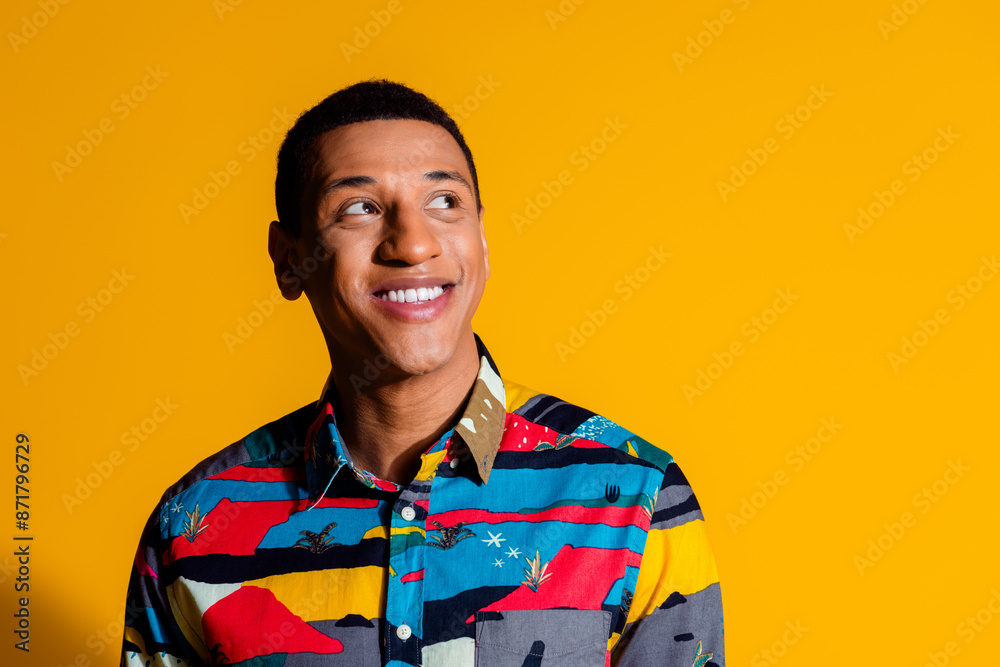 Photo portrait of handsome young guy look empty space wear trendy colorful outfit isolated on yellow color background Photo portrait of handsome young guy look empty space wear trendy colorful outfit isolated on yellow color background