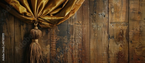 Tassel from a gold curtain hangs on a wooden wall providing a copyspace image. photo