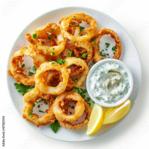 A plate of Greek kalamari, crispy fried squid rings served with a side of lemon wedges and tzatziki sauce, isolated on white background. photo