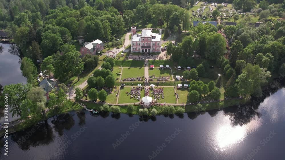 Aerial view of the small town of Birin Castle, located in a green park. The parish is surrounded by well-maintained paths, trees and open grass. Residential buildings and a lake Aerial view of the small town of Birin Castle, located in a green park. The parish is surrounded by well-maintained paths, trees and open grass. Residential buildings and a lake