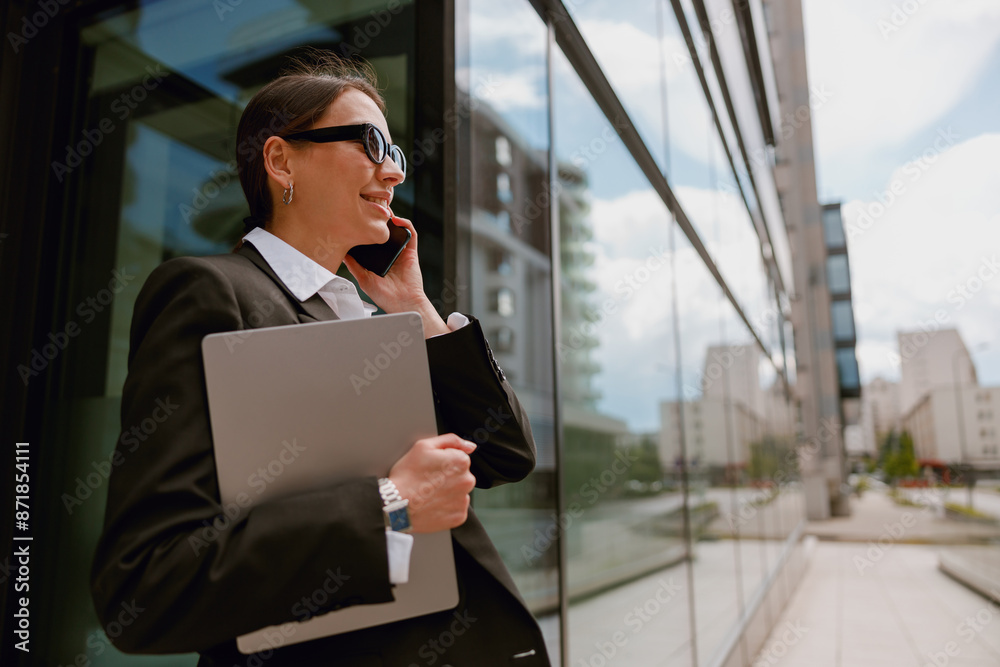 Business professional in modern cityscape talking on phone and holding documents Business professional in modern cityscape talking on phone and holding documents