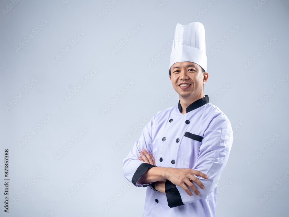 A confident Asian male chef in a white uniform and hat, standing with arms crossed and smiling, exudes professionalism and expertise against a light blue background A confident Asian male chef in a white uniform and hat, standing with arms crossed and smiling, exudes professionalism and expertise against a light blue background