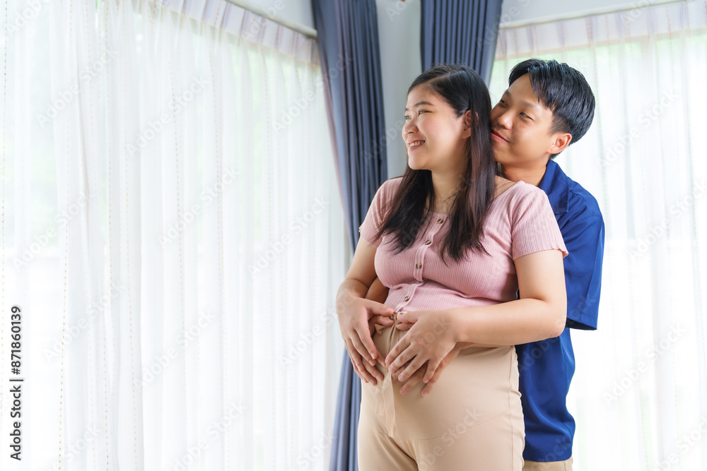An Asian young husband gently embraces his pregnant wife at home, their love evident as they prepare for parenthood, cherishing the tender moments of expecting their first child together. An Asian young husband gently embraces his pregnant wife at home, their love evident as they prepare for parenthood, cherishing the tender moments of expecting their first child together.