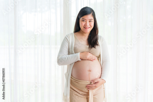 An Asian young pregnant wife relaxes at home, her hand gently resting on her belly, filled with love and anticipation as she embraces the journey of impending motherhood. Free Download An Asian young pregnant wife relaxes at home, her hand gently resting on her belly, filled with love and anticipation as she embraces the journey of impending motherhood. - GFXLoad
