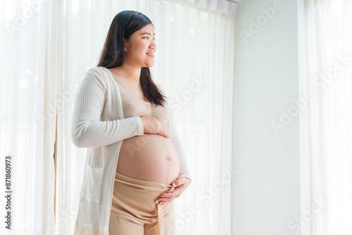 An Asian young pregnant wife relaxes at home, her hand gently resting on her belly, filled with love and anticipation as she embraces the journey of impending motherhood. Free Download An Asian young pregnant wife relaxes at home, her hand gently resting on her belly, filled with love and anticipation as she embraces the journey of impending motherhood. - GFXLoad