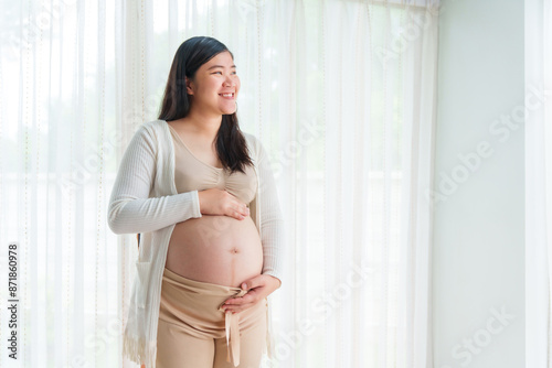 An Asian young pregnant wife relaxes at home, her hand gently resting on her belly, filled with love and anticipation as she embraces the journey of impending motherhood. Free Download An Asian young pregnant wife relaxes at home, her hand gently resting on her belly, filled with love and anticipation as she embraces the journey of impending motherhood. - GFXLoad